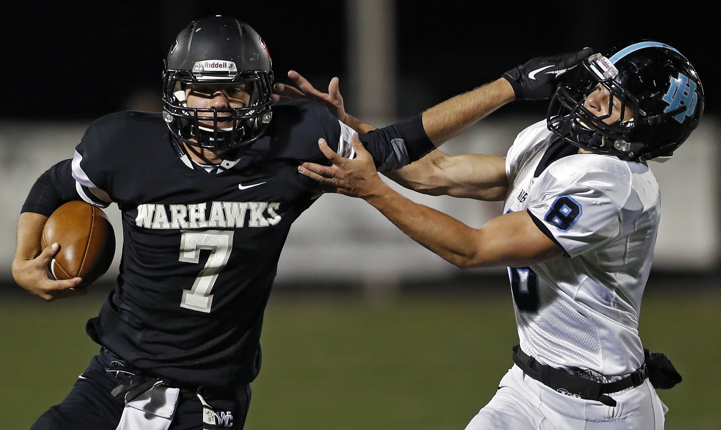 Two football players fighting for position on a field.