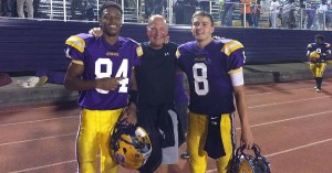 Three football players posing for a picture with their coach.