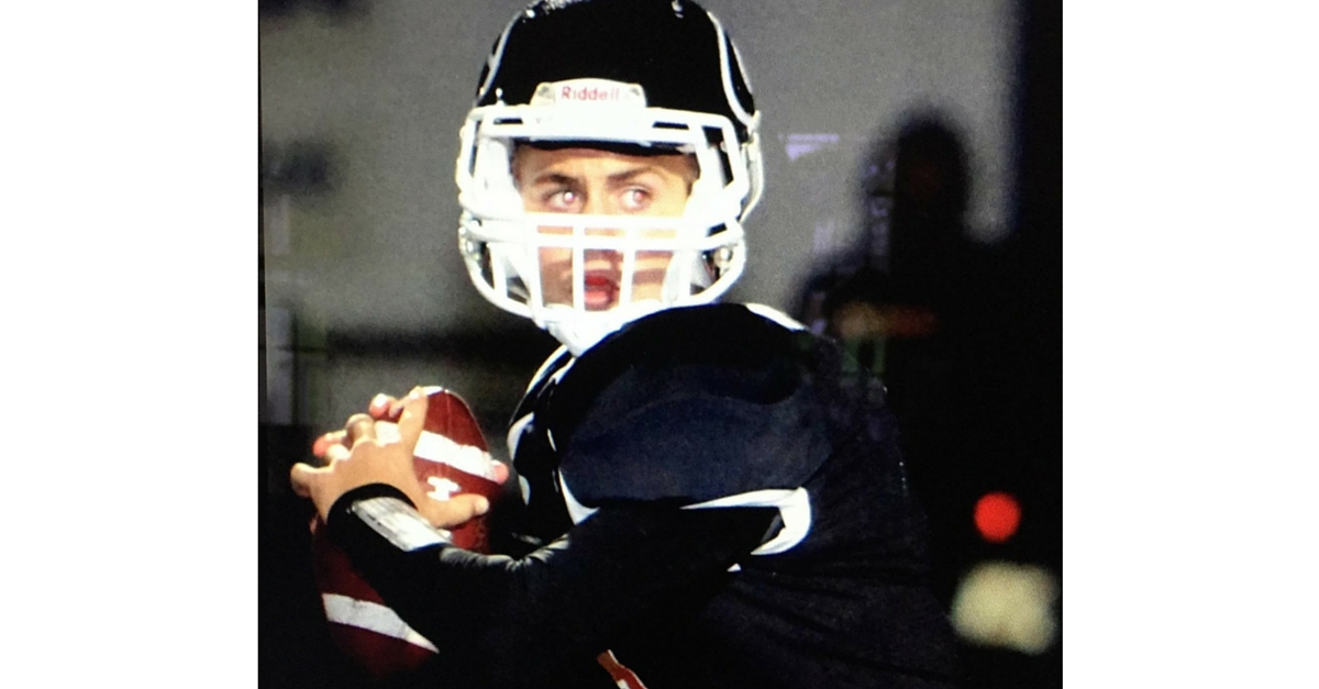 A football player holding a ball and wearing a helmet.