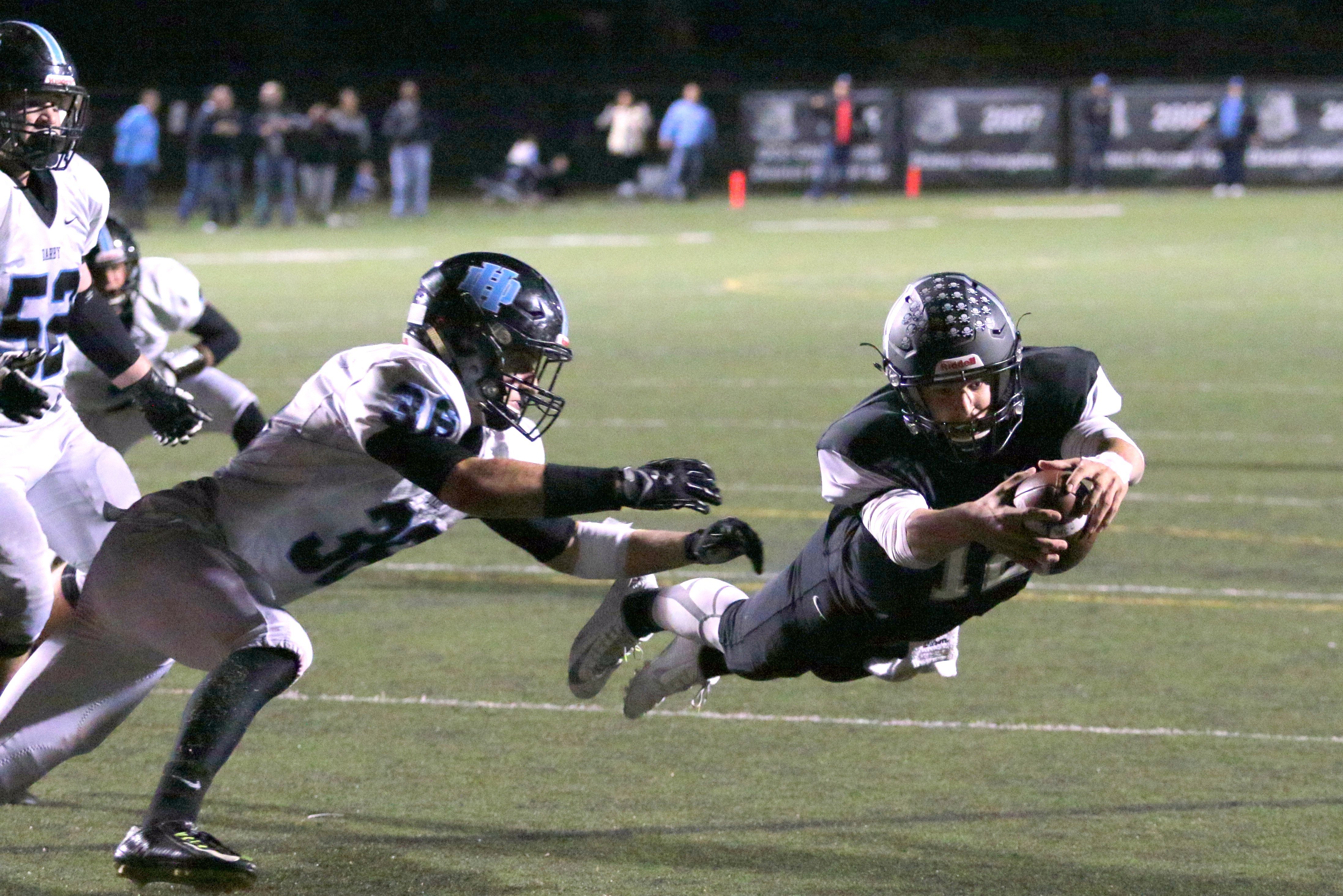 A football player dives for the goal line.