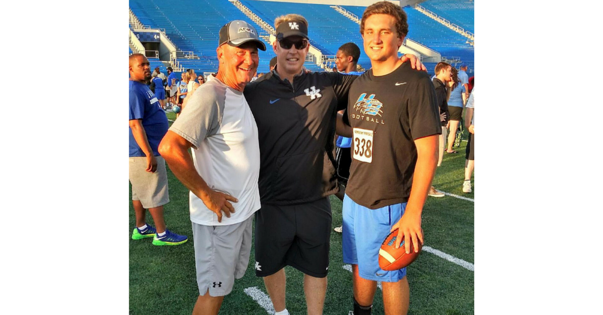 Three men standing on a field with an american football.