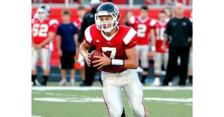 A football player holding a ball on top of a field.