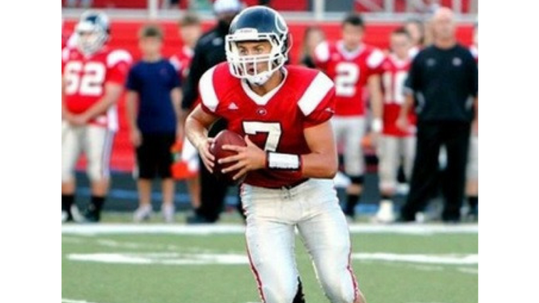 A football player holding a ball on top of a field.