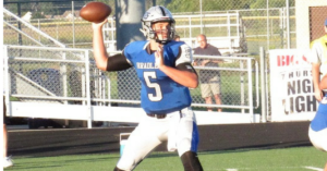 A man in blue and white uniform throwing a football.