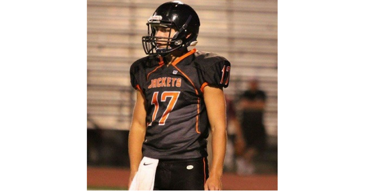 A football player in uniform is standing on the field.