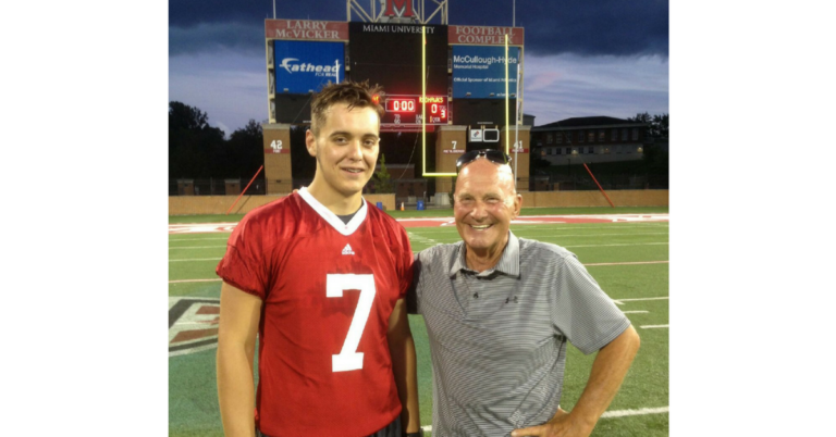 A man and a boy standing on top of a football field.