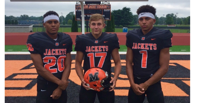 Three football players are posing for a picture.