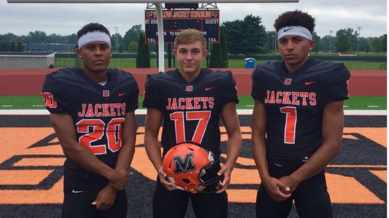 Three football players are posing for a picture.