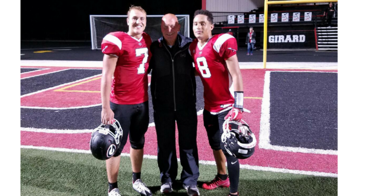 Three football players posing for a picture with their coach.