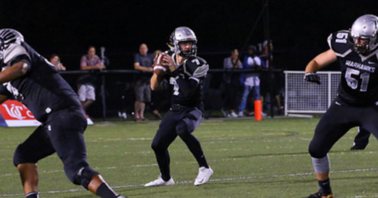 A football player holding a ball and looking at the camera.