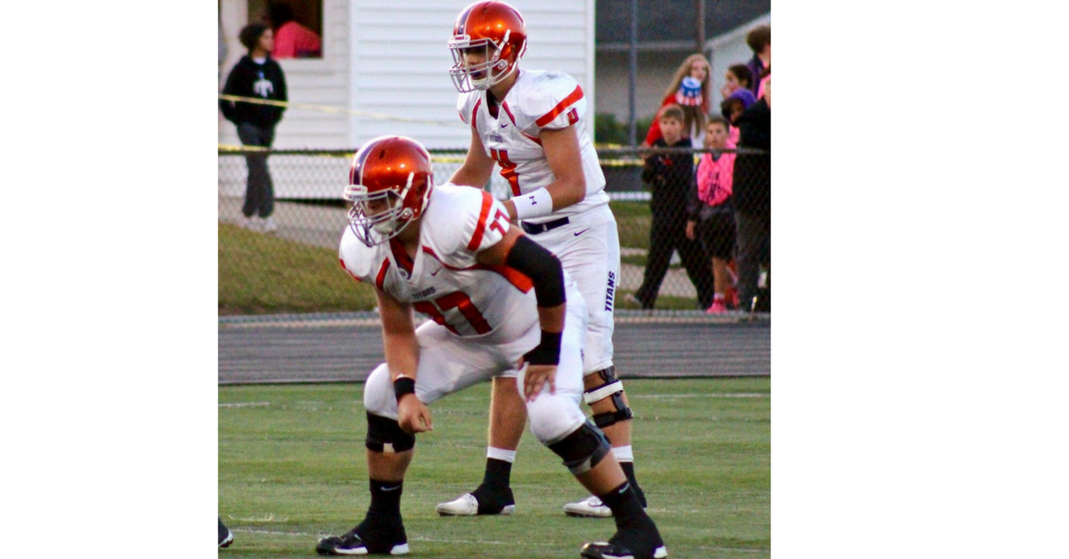 Two football players are standing on a field.