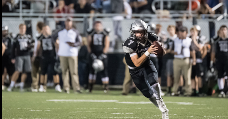 A football player running with the ball in his hands.