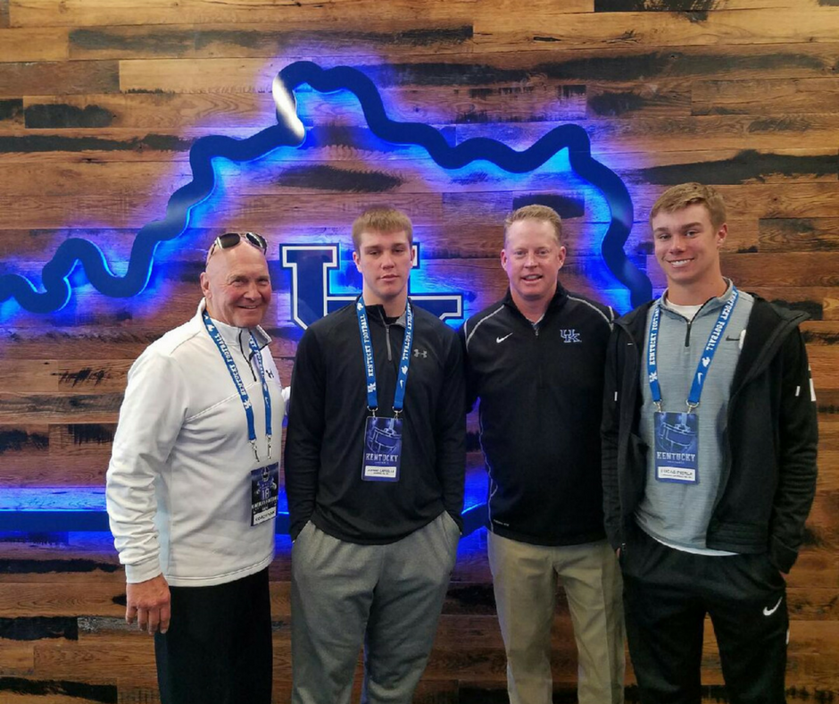 Four men standing in front of a blue sign.