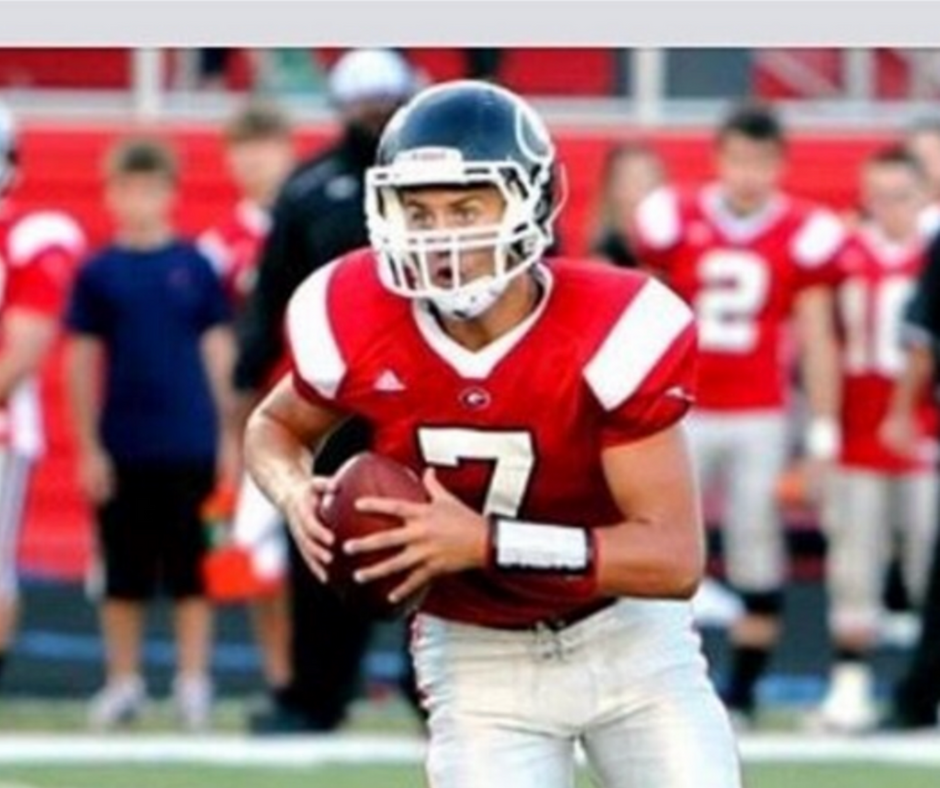 A football player holding a ball on the field.