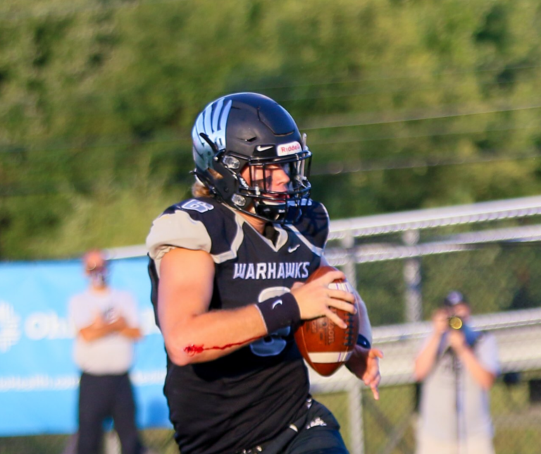 A football player holding a ball while wearing a helmet.