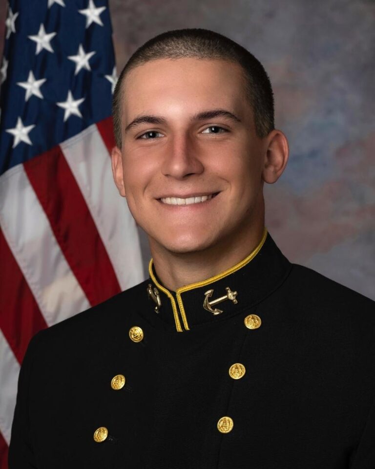 A man in military uniform standing next to an american flag.